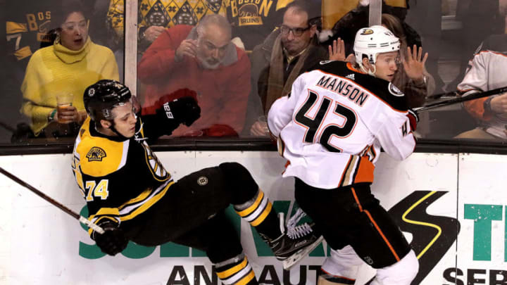BOSTON - JANUARY 30: Boston Bruins left wing Jake DeBrusk (74) takes a hit along the boards from Anaheim Ducks' Josh Manson (42) during the first period. The Boston Bruins host the Anaheim Ducks in a regular season NHL hockey game at TD Garden in Boston on Jan. 30, 2018. (Photo by Barry Chin/The Boston Globe via Getty Images)