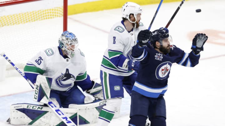 Mar 1, 2021; Winnipeg, Manitoba, CAN; Vancouver Canucks defenseman Jordie Benn (8) and Winnipeg Jets left wing Mathieu Perreault (85) eye the puck in front of Vancouver Canucks goaltender Thatcher Demko (35) in the third period at Bell MTS Place. Mandatory Credit: James Carey Lauder-USA TODAY Sports
