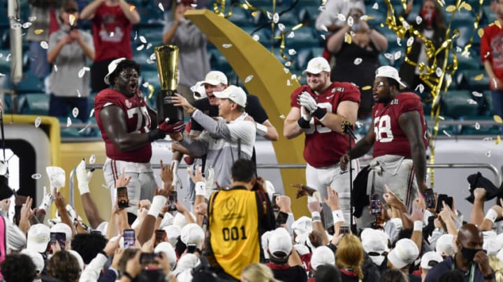 MIAMI GARDENS, FLORIDA - JANUARY 11: Head coach Nick Saban and Alex Leatherwood #70 of the Alabama Crimson Tide hold up the CFP National Championship Trophy on the trophy presentation stage with Mac Jones #10, Landon Dickerson #69, Christian Barmore #58, and DeVonta Smith #6 after the College Football Playoff National Championship football game against the Ohio State Buckeyes at Hard Rock Stadium on January 11, 2021 in Miami Gardens, Florida. The Alabama Crimson Tide defeated the Ohio State Buckeyes 52-24. (Photo by Alika Jenner/Getty Images)