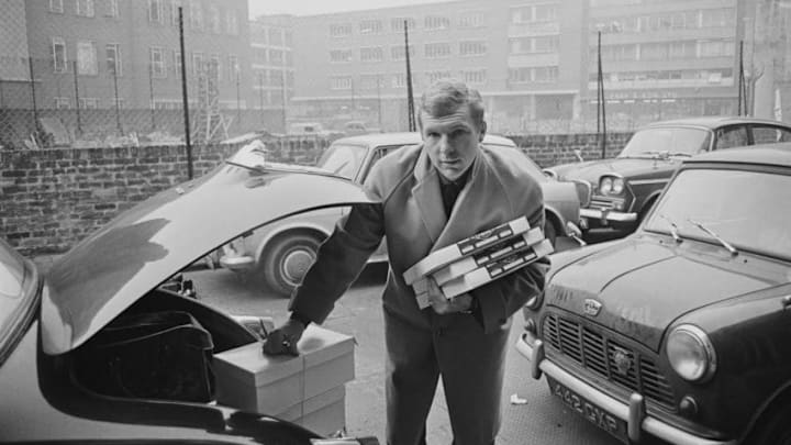 English professional footballer and defender with West Ham United, Bobby Moore (1941-1993) pictured loading parcels in to the boot of his Jaguar car after a christmas shopping trip on 24th December 1964. (Photo by Norman Quicke/Daily Express/Hulton Archive/Getty Images)