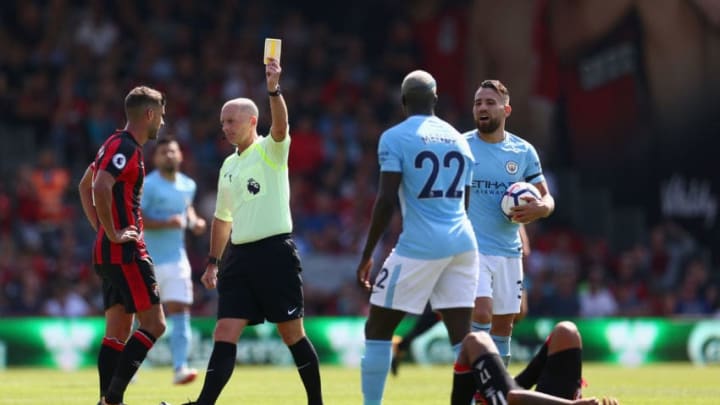 BOURNEMOUTH, ENGLAND - AUGUST 26: Referee Mike Dean shows Benjamin Mendy of Manchester City a yellow card during the Premier League match between AFC Bournemouth and Manchester City at Vitality Stadium on August 26, 2017 in Bournemouth, England. (Photo by Steve Bardens/Getty Images)