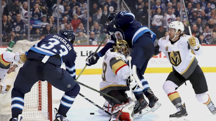 WINNIPEG, MB - FEBRUARY 1: Dustin Byfuglien #33 and Blake Wheeler #26 of the Winnipeg Jets reach around goaltender Marc-Andre Fleury #29 of the Vegas Golden Knights for the loose puck in the crease during the overtime period at the Bell MTS Place on February 1, 2018 in Winnipeg, Manitoba, Canada. (Photo by Darcy Finley/NHLI via Getty Images)