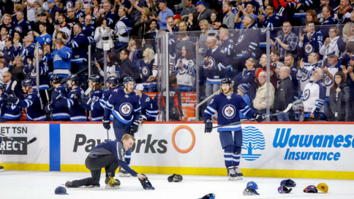 WINNIPEG, MB - MARCH 23: Kevin Hayes #12 and Kyle Connor #81 of the Winnipeg Jets watch as a member of the Ice Crew picks up hats that litter the ice for Connor's third period hat trick goal against the Nashville Predators at the Bell MTS Place on March 23, 2019 in Winnipeg, Manitoba, Canada. (Photo by Darcy Finley/NHLI via Getty Images)