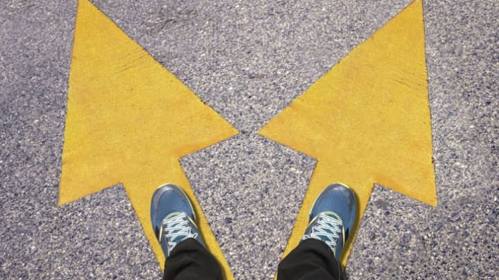 A pair of blue shoes on the ground with yellow arrows pointing in two different directions