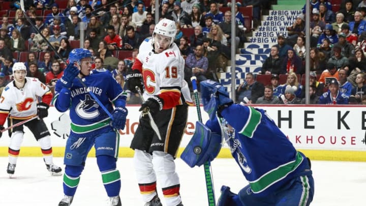 VANCOUVER, BC - DECEMBER 17: Troy Stecher #51 of the Vancouver Canucks and Matthew Tkachuk #19 of the Calgary Flames look on as Anders Nilsson #31 of the Vancouver Canucks makes a save during their NHL game at Rogers Arena December 17, 2017 in Vancouver, British Columbia, Canada. (Photo by Jeff Vinnick/NHLI via Getty Images)"n