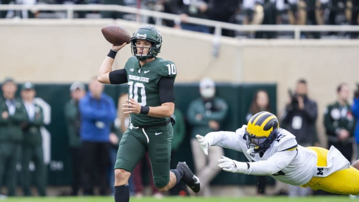 Oct 30, 2021; East Lansing, Michigan, USA; Michigan State Spartans quarterback Payton Thorne (10) looks to throw the ball as Michigan Wolverines defensive lineman Christopher Hinton (15) dives after him during the first quarter at Spartan Stadium. Mandatory Credit: Raj Mehta-USA TODAY Sports