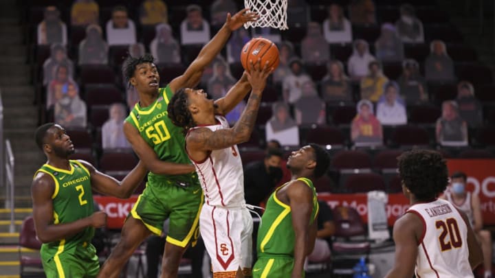LOS ANGELES, CA - FEBRUARY 22: Isaiah White #5 of the USC Trojans is fouled by Eric Williams Jr. #50 as Amauri Hardy #11 of the Oregon Ducks looks on at Galen Center on February 22, 2021 in Los Angeles, California. USC won 72-58. (Photo by John McCoy/Getty Images)