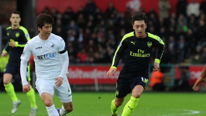 SWANSEA, WALES - JANUARY 14: Mesut Ozil of Arsenal takes on Ki Sung-Yueng of Swansea during the Premier League match between Swansea City and Arsenal at Liberty Stadium on January 14, 2017 in Swansea, Wales. (Photo by David Price/Arsenal FC via Getty Images)