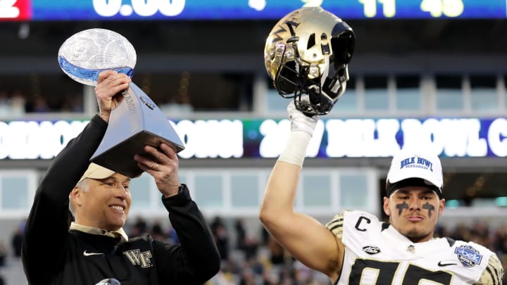 CHARLOTTE, NC – DECEMBER 29: Head coach Dave Clawson and player Cam Serigne #85 of the Wake Forest Demon Deacons celebrate with the trophy after defeating the Texas A&M Aggies 55-52 after the Belk Bowl at Bank of America Stadium on December 29, 2017 in Charlotte, North Carolina. (Photo by Streeter Lecka/Getty Images)