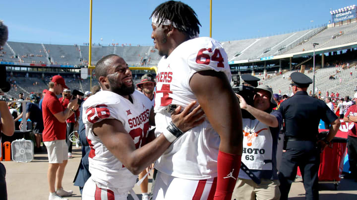 Oklahoma’s Kennedy Brooks (26) celebrates with Wanya Morris (64) after the Red River Showdown college football game between the University of Oklahoma Sooners (OU) and the University of Texas (UT) Longhorns at the Cotton Bowl in Dallas, Saturday, Oct. 9, 2021. Oklahoma won 55-48.Ou Vs Texas