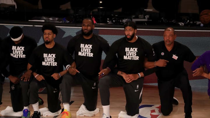 LAKE BUENA VISTA, FLORIDA – JULY 30: LeBron James #23 and Anthony Davis #3 of the Los Angeles Lakers in a Black Lives Matter Shirt kneel with their teammates during the national anthem prior to the game against the LA Clippers at The Arena at ESPN Wide World Of Sports Complex on July 30, 2020 in Lake Buena Vista, Florida. NOTE TO USER: User expressly acknowledges and agrees that, by downloading and or using this photograph, User is consenting to the terms and conditions of the Getty Images License Agreement. (Photo by Mike Ehrmann/Getty Images)