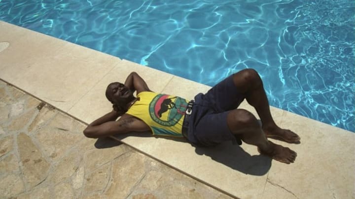 Jul 1990: Roger Milla striker of the Cameroon team relaxes by a swimming pool during the World Cup in Italy. Mandatory Credit: Allsport UK /Allsport