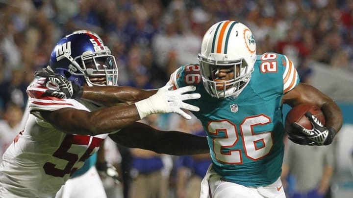 Dec 14, 2015; Miami Gardens, FL, USA; New York Giants linebacker J.T. Thomas (55) is stiff armed by Miami Dolphins running back Lamar Miller (26) as he scores on a first quarter run at Sun Life Stadium. Mandatory Credit: Andrew Innerarity-USA TODAY Sports