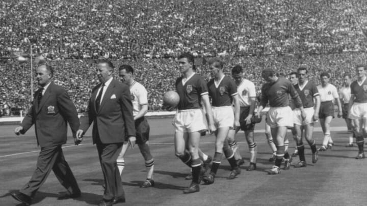 The Manchester United Football team is led out on to the field by Acting-Manager Jimmy Murphy and team captain Bill Foulkes together with Bolton Wanderers Manager Bill Ridding and team captain Nat Lofthouse before the kick off of their FA Cup Final match on 3rd May 1958 at Wembley Stadium, London, United Kingdom. Bolton Wanderers won the game 2 -0 . (Photo by Evening Standard/Hulton Archive/Getty Images).