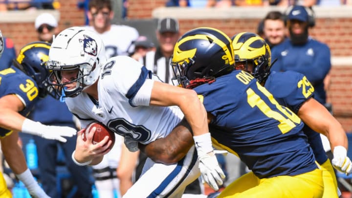 ANN ARBOR, MICHIGAN - SEPTEMBER 17: Cale Millen #10 of the Connecticut Huskies is sacked by Eyabi Okie #18 of the Michigan Wolverines during the second half of a college football game at Michigan Stadium on September 17, 2022 in Ann Arbor, Michigan. The Michigan Wolverines won the game 59-0 over the Connecticut Huskies. (Photo by Aaron J. Thornton/Getty Images)