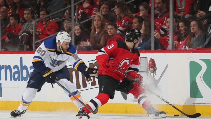 NEWARK, NJ - MARCH 30: Nico Hischier #13 of the New Jersey Devils and Ryan O'Reilly #90 of the St. Louis Blues battle for a loose puck during the game at Prudential Center on March 30, 2019 in Newark, New Jersey. (Photo by Andy Marlin/NHLI via Getty Images)