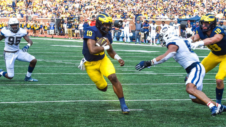 ANN ARBOR, MICHIGAN – SEPTEMBER 17: Alex Orji #10 of the Michigan Wolverines runs for a touchdown after avoiding a tackle by Ian Swenson #6 of the Connecticut Huskies during the second half of a college football game at Michigan Stadium on September 17, 2022 in Ann Arbor, Michigan. The Michigan Wolverines won the game 59-0 over the Connecticut Huskies. (Photo by Aaron J. Thornton/Getty Images)