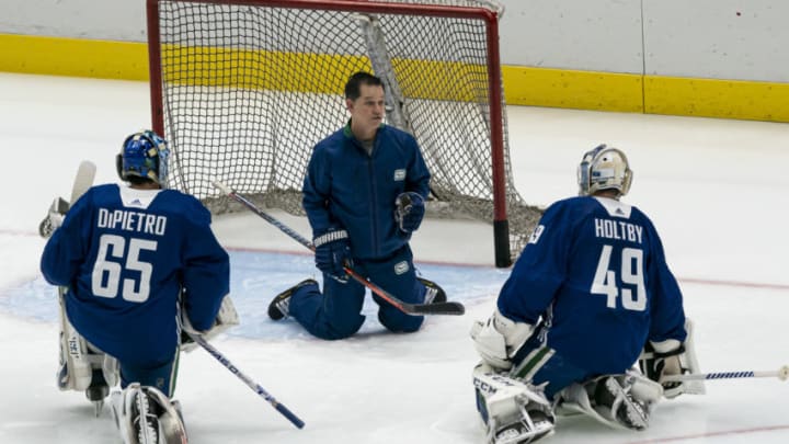 VANCOUVER, BC - JANUARY 4: Goalie coach Ian Clark of the Vancouver Canucks works with goalies Michael Dipietro #65 and Braden Holtby #49 on the first day of the Vancouver Canucks NHL Training Camp on January, 4, 2021 at Rogers Arena in Vancouver, British Columbia, Canada. (Photo by Rich Lam/Getty Images)