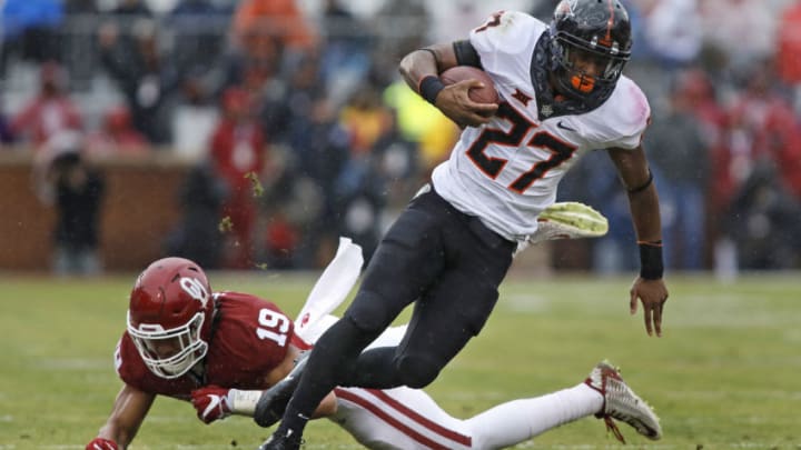 NORMAN, OK - DECEMBER 3: Running back Justice Hill #27 of the Oklahoma State Cowboys makes it past linebacker Caleb Kelly #19 of the Oklahoma Sooners December 3, 2016 at Gaylord Family-Oklahoma Memorial Stadium in Norman, Oklahoma. Oklahoma defeated Oklahoma State 38-20 to become Big XII champions. (Photo by Brett Deering/Getty Images)