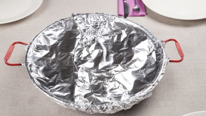 A round dish covered in foil sits on a table.
