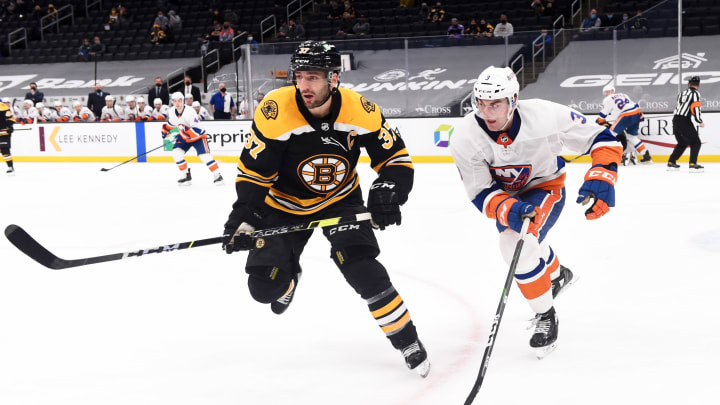 Mar 25, 2021; Boston, Massachusetts, USA; Boston Bruins center Patrice Bereron (37) and New York Islanders defenseman Adam Pelech (3) skate after the puck during the third period at TD Garden. Mandatory Credit: Bob DeChiara-USA TODAY Sports