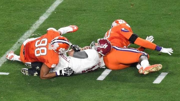 Jan 11, 2016; Glendale, AZ, USA; Alabama Crimson Tide quarterback Jake Coker (14) is brought down by Clemson Tigers defensive end Shaq Lawson (90) and defensive end Kevin Dodd (98) during the first quarter in the 2016 CFP National Championship at University of Phoenix Stadium. Mandatory Credit: Gary A. Vasquez-USA TODAY Sports