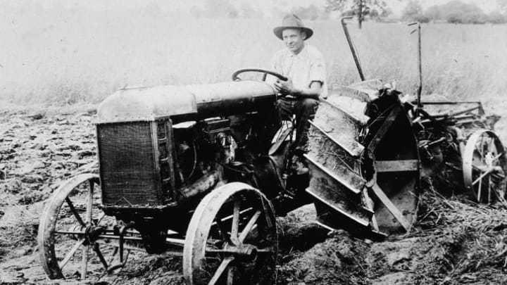 A man sits in the driver seat of the first Ford tractor, circa 1920.