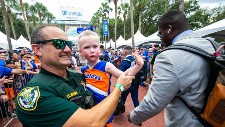 Lt. Hood of the Alachua County Sheriff’s Office holds a young Florida fan as she wave to the Gator players during Gator Walk as they were greeted by fans before playing the Tennessee Volunteers Saturday September 25, 2021 at Ben Hill Griffin Stadium in Gainesville, FL. [Doug Engle/GainesvilleSun]2021Flgai 092521 Gatorsvsvolsgatorwalk