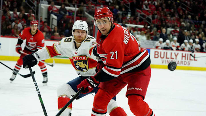 RALEIGH, NC - DECEMBER 21: Nino Niederreiter #21 of the Carolina Hurricanes keeps his eye on a loose puck as Mike Matheson #19 of the Florida Panthers defends during an NHL game on December 21, 2019 at PNC Arena in Raleigh, North Carolina. (Photo by Gregg Forwerck/NHLI via Getty Images)