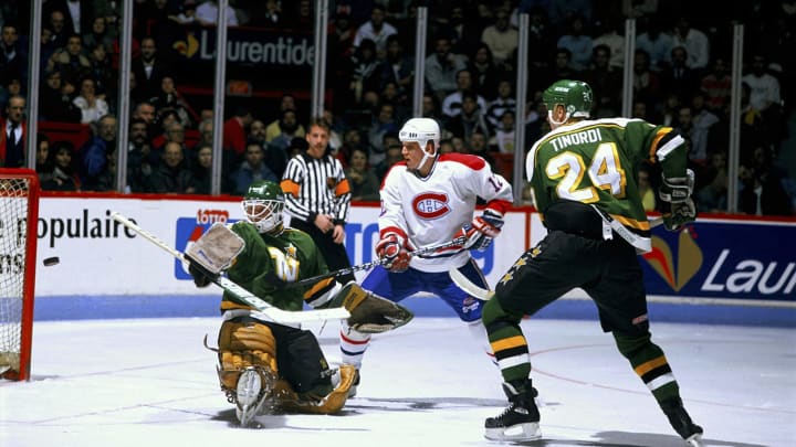 MONTREAL – CIRCA 1980: Mike Keane #12 of the Montreal Canadiens shoots the puck past goaltender Jon Casey #30 and defenseman Mark Tinordi #24 of the Minnesota North Stars in a game at the Montreal Forum circa 1980 in Montreal, Quebec, Canada. (Photo by Denis Brodeur/NHLI via Getty Images)