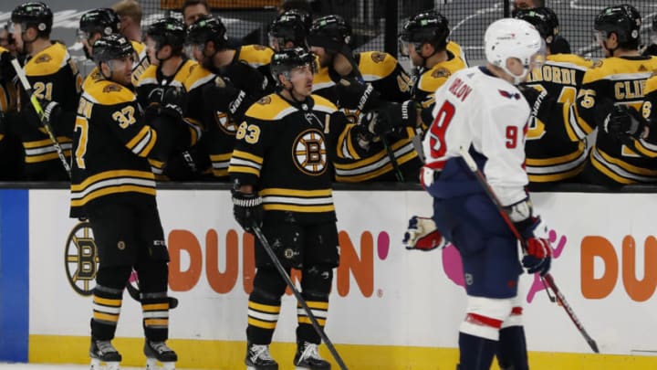 Apr 18, 2021; Boston, Massachusetts, USA; Boston Bruins center Brad Marchand (63) and center Patrice Bergeron (37) are congratulated at the bench after Marchand scored as Washington Capitals defenseman Dmitry Orlov (9) skates away during the second period at TD Garden. Mandatory Credit: Winslow Townson-USA TODAY Sports