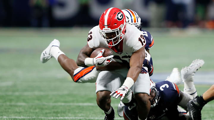 ATLANTA, GA – DECEMBER 02: Elijah Holyfield #13 of the Georgia Bulldogs is tackled by Jamel Dean #12 of the Auburn Tigers on a run during the second half against the Auburn Tigers in the SEC Championship at Mercedes-Benz Stadium on December 2, 2017, in Atlanta, Georgia. (Photo by Jamie Squire/Getty Images)