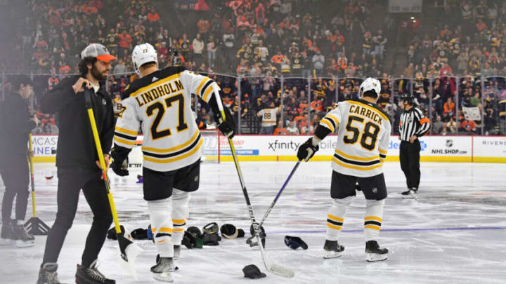 Apr 9, 2023; Philadelphia, Pennsylvania, USA; Boston Bruins defenseman Hampus Lindholm (27) and defenseman Connor Carrick (58) help gather the hats on the ice after right wing David Pastrnak (88) (not pictured) scored a hat trick against the Philadelphia Flyers during the third period at Wells Fargo Center. Mandatory Credit: Eric Hartline-USA TODAY Sports