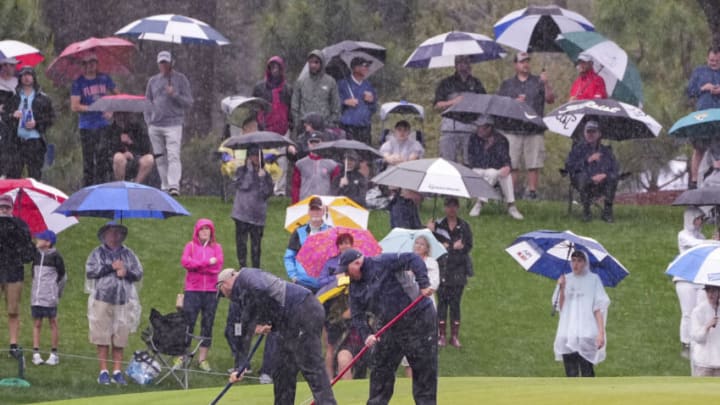 Mar 11, 2022; Ponte Vedra Beach, Florida, USA; Grounds crews use squeegees on the 11th green as rain continues to fall during the first round of THE PLAYERS Championship golf tournament. Mandatory Credit: David Yeazell-USA TODAY Sports