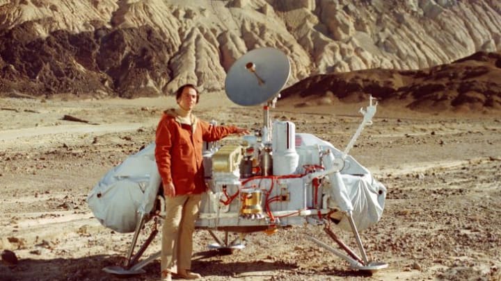 Carl Sagan posing with a model of the Viking lander in Death Valley, California.