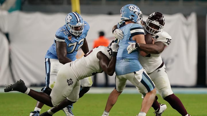 Jan 2, 2021; Miami Gardens, FL, USA; North Carolina Tar Heels quarterback Sam Howell (7) is taken down by Texas A&M Aggies defensive lineman Jeremiah Martin (15), left, and defensive lineman McKinnley Jackson (35) during the second half at Hard Rock Stadium. Mandatory Credit: Jasen Vinlove-USA TODAY Sports