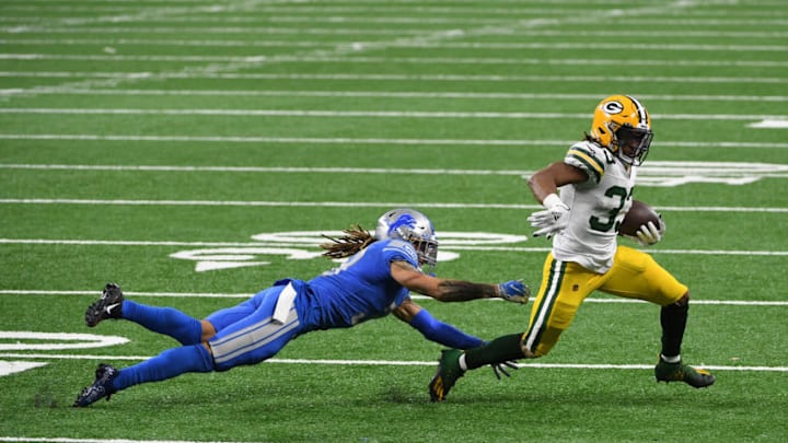 DETROIT, MICHIGAN - DECEMBER 13: Mike Ford #38 of the Detroit Lions attempts to tackle Aaron Jones #33 of the Green Bay Packers during the second half at Ford Field on December 13, 2020 in Detroit, Michigan. (Photo by Nic Antaya/Getty Images)
