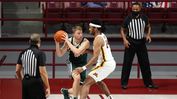 Dec 28, 2020; Minneapolis, Minnesota, USA; Michigan State Spartans forward Thomas Kithier (15) dribbles the ball as Minnesota Gophers forward Eric Curry (24) guards him during the first half at Williams Arena. Mandatory Credit: Harrison Barden-USA TODAY Sports