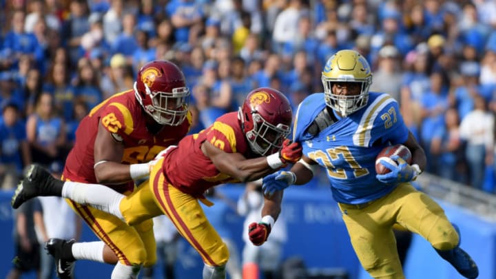 PASADENA, CALIFORNIA - NOVEMBER 17: Joshua Kelley #27 of the UCLA Bruins runs as he is chased by John Houston Jr. #10 and Keyshawn Young #85 of the USC Trojans during the first half at Rose Bowl on November 17, 2018 in Pasadena, California. (Photo by Harry How/Getty Images)