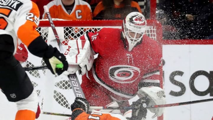 RALEIGH, NC - DECEMBER 31: Travis Konecny #11 of the Philadelphia Flyers loses an edge and collides with Curtis McElhinney #35 of the Carolina Hurricanes in the crease during an NHL game on December 31, 2018 at PNC Arena in Raleigh, North Carolina. (Photo by Gregg Forwerck/NHLI via Getty Images)