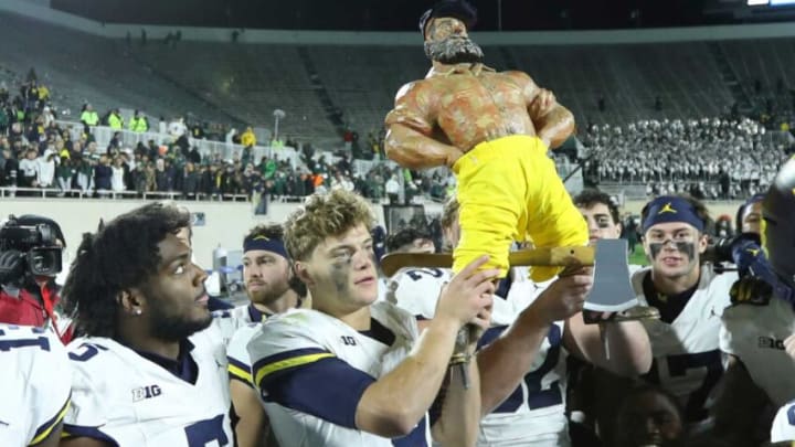 Michigan Wolverines quarterback J.J. McCarthy (9) hoists the Paul Bunyan Trophy after the 49-0 win against the Michigan State Spartans at Spartan Stadium in East Lansing on Saturday, Oct. 21, 2023.