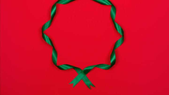 A curly green ribbon in the shape of a wreath on a red background.