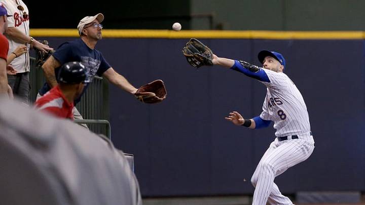 MILWAUKEE, WI - JULY 06: Ryan Braun #8 of the Milwaukee Brewers and a fan reach to catch a fly ball in the seventh inning against the Atlanta Braves at Miller Park on July 6, 2018 in Milwaukee, Wisconsin. (Photo by Dylan Buell/Getty Images)