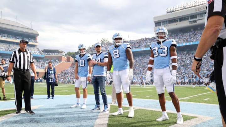 CHAPEL HILL, NC - SEPTEMBER 24: Umpire Jim Eckl, and Drake Maye #10, Myles Murphy #8, Cedric Gray #33, and honorary captain and recording artist Eric Church #34 listen to pregame instructions from Referee Jeff Flanagan before a game between Notre Dame and North Carolina at Kenan Memorial Stadium on September 24, 2022 in Chapel Hill, North Carolina. (Photo by Andy Mead/ISI Photos/Getty Images)