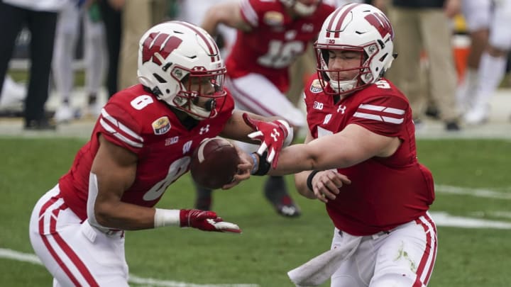 Dec 30, 2020; Charlotte, NC, USA; Wisconsin Badgers quarterback Graham Mertz (5) hands off to running back Jalen Berger (8) during second quarter action against the Wake Forest Demon Deacons at Bank of America Stadium. Mandatory Credit: Jim Dedmon-USA TODAY Sports