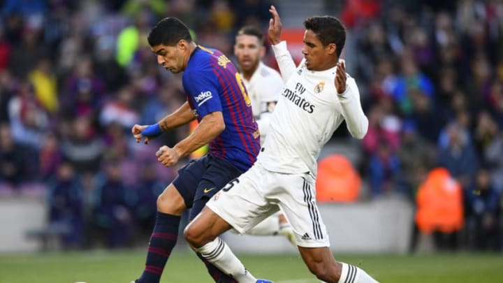 Real Madrid's French defender Raphael Varane (R) fouls Barcelona's Uruguayan forward Luis Suarez during the Spanish league football match between FC Barcelona and Real Madrid CF at the Camp Nou stadium in Barcelona on October 28, 2018. (Photo by GABRIEL BOUYS / AFP) (Photo credit should read GABRIEL BOUYS/AFP/Getty Images)