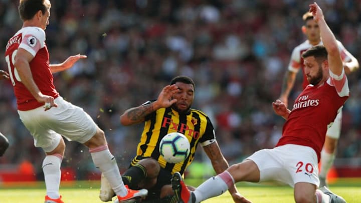 Watford's English striker Troy Deeney (C) slides in against Arsenal's German defender Shkodran Mustafi (R) and Arsenal's Spanish defender Nacho Monreal (L) during the English Premier League football match between Arsenal and Watford at the Emirates Stadium in London on September 29, 2018. (Photo by Adrian DENNIS / AFP) / RESTRICTED TO EDITORIAL USE. No use with unauthorized audio, video, data, fixture lists, club/league logos or 'live' services. Online in-match use limited to 120 images. An additional 40 images may be used in extra time. No video emulation. Social media in-match use limited to 120 images. An additional 40 images may be used in extra time. No use in betting publications, games or single club/league/player publications. / (Photo credit should read ADRIAN DENNIS/AFP/Getty Images)