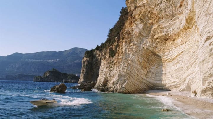 A speedboat skims across the water of the Ionian sea close to a deserted beach cove near the resort of Paleokastritsa, on the Greek Island of Corfu, Greece, in April 1996. (Photo by Bryn Colton/Getty Images)