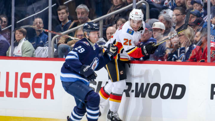 WINNIPEG, MB - DECEMBER 27: Patrik Laine #29 of the Winnipeg Jets checks Garnet Hathaway #21 of the Calgary Flames into the boards during first period action at the Bell MTS Place on December 27, 2018 in Winnipeg, Manitoba, Canada. (Photo by Jonathan Kozub/NHLI via Getty Images)