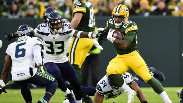 GREEN BAY, WISCONSIN - NOVEMBER 14: A.J. Dillon #28 of the Green Bay Packers carries the ball against Jamal Adams #33 and Quandre Diggs #6 of the Seattle Seahawks during the first quarter at Lambeau Field on November 14, 2021 in Green Bay, Wisconsin. (Photo by Patrick McDermott/Getty Images)